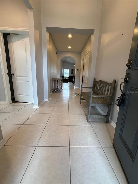 A tiled entryway leads into a hallway with a wooden bench and recessed lighting — 1165 HILLTOP PLACE, ST CLOUD, FL