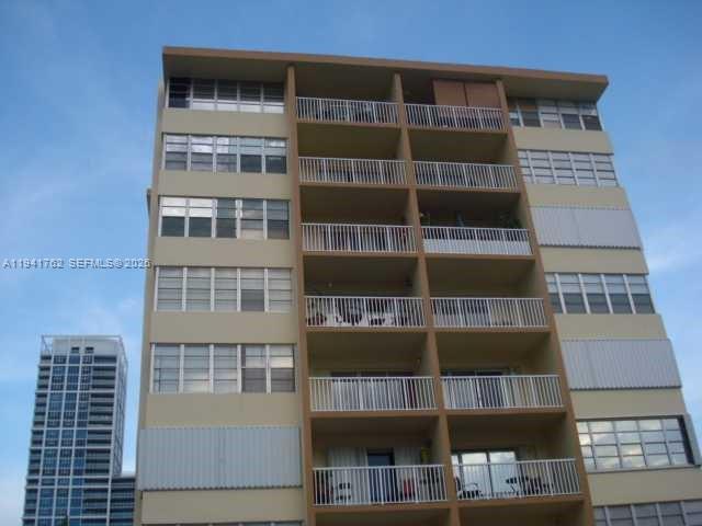 A low-angle exterior view of a multi-story apartment building with balconies and large windows — 6855 Abbott Ave # 601, Miami Beach FL 33141, MIAMI BEACH, FL