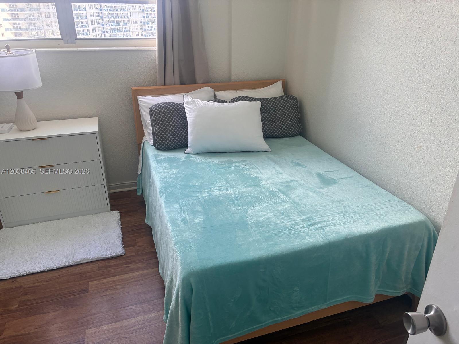 A bedroom features a light blue blanket on a wooden bed frame next to a dresser — 3901 S Ocean Dr # 14Q, Hollywood FL 33019, HOLLYWOOD, FL