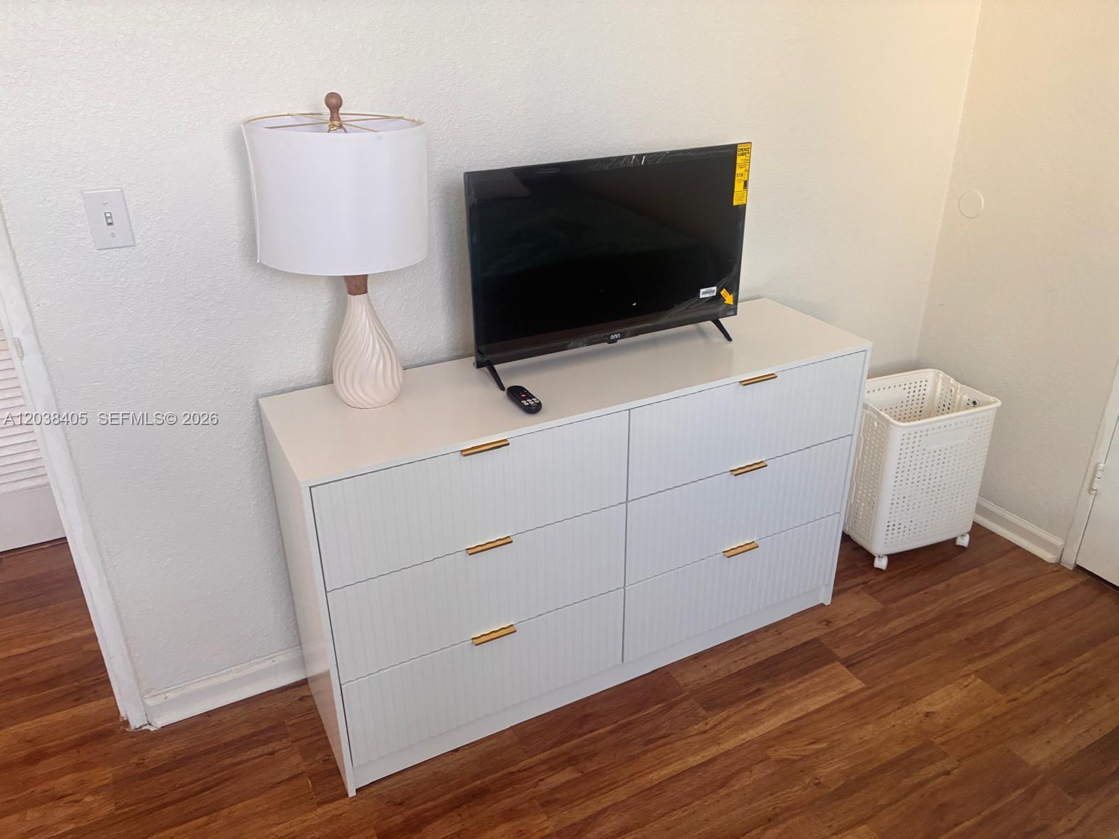 A white dresser with gold handles holds a television and lamp in a bedroom — 3901 S Ocean Dr # 14Q, Hollywood FL 33019, HOLLYWOOD, FL