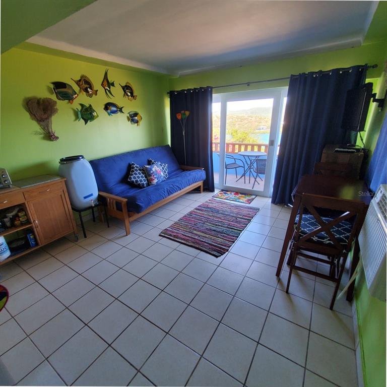 A living room with a blue futon, tile floors, green walls, and a balcony view — D101 BAHIA MARINA CONDOMINIUM RESORT UNIT D101, CULEBRA, PR