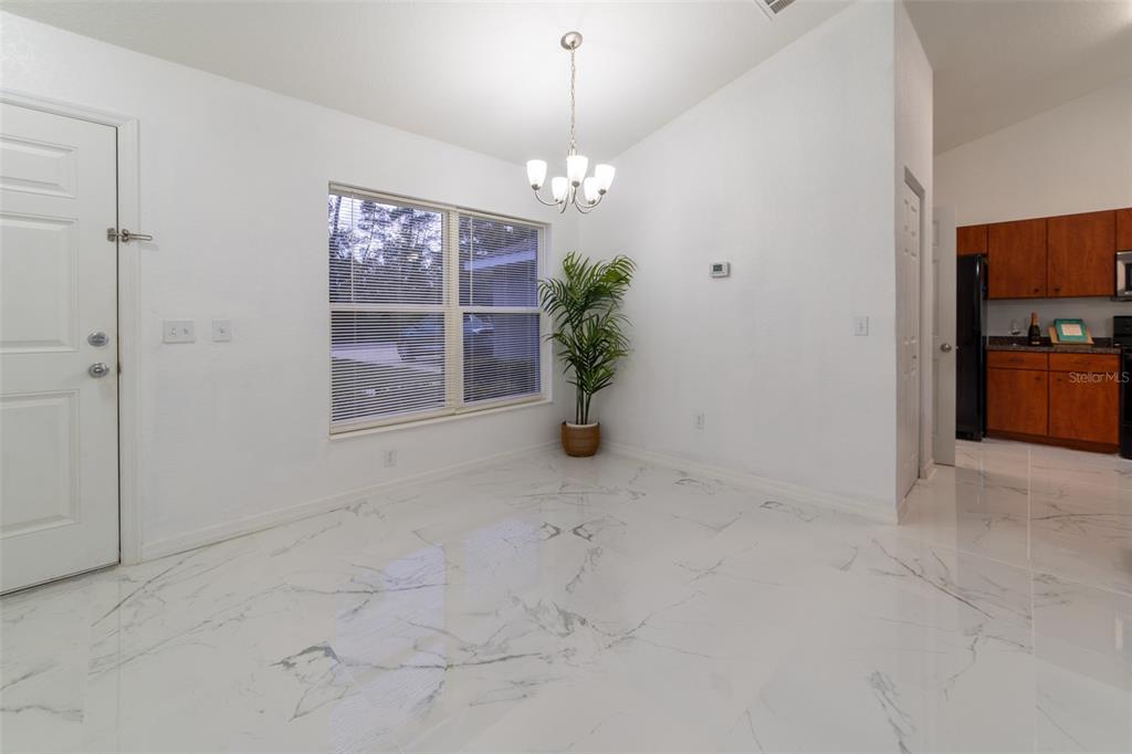 A dining area features white walls, marble-look tile flooring, a chandelier, and a potted plant — 5107 SW 165TH STREET ROAD, OCALA, FL