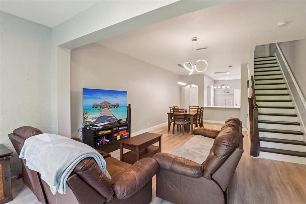 A living room with brown leather furniture, a television, and a dining area near stairs — 3661 COUNTRY POINTE PLACE, PALM HARBOR, FL