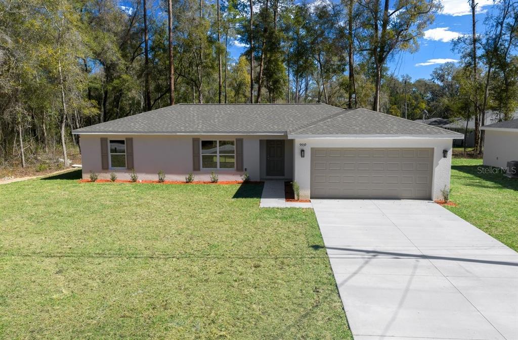 A single-story house with a beige exterior, gray shutters, and a concrete driveway — 9939 N ATHENIA DRIVE, CITRUS SPRINGS, FL