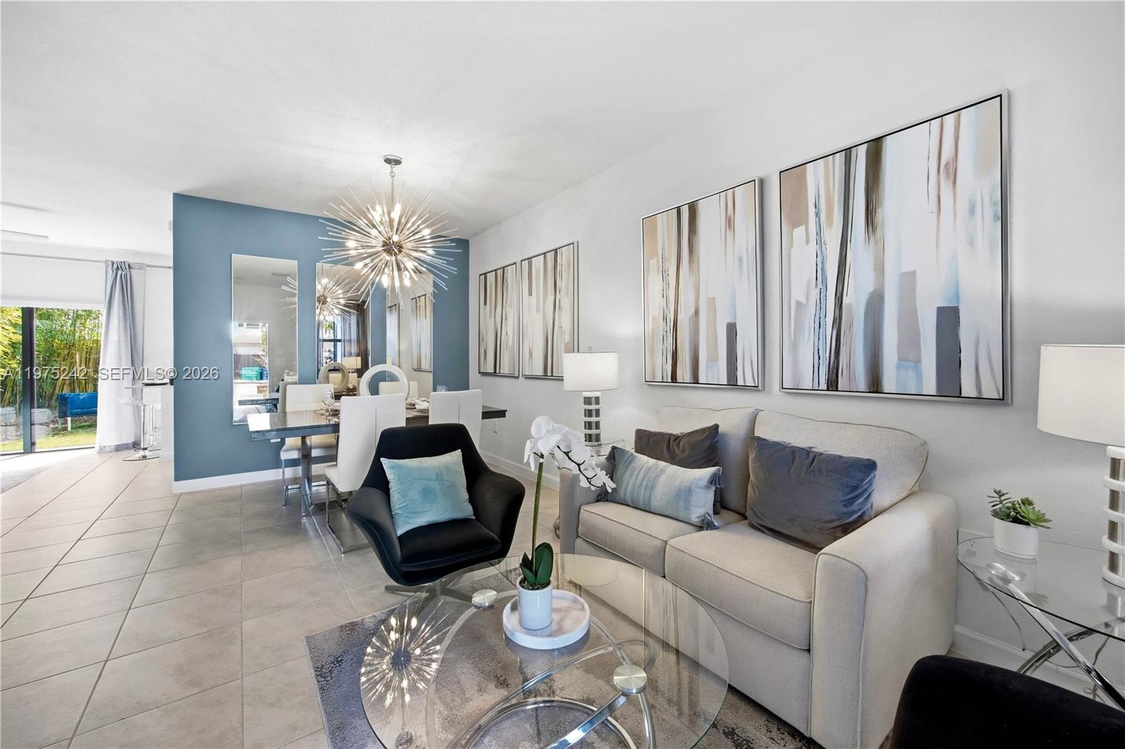 A living and dining area features a sofa, black armchair, glass table, and blue wall — 13054 SW 233rd Ter, Homestead FL 33032, HOMESTEAD, FL