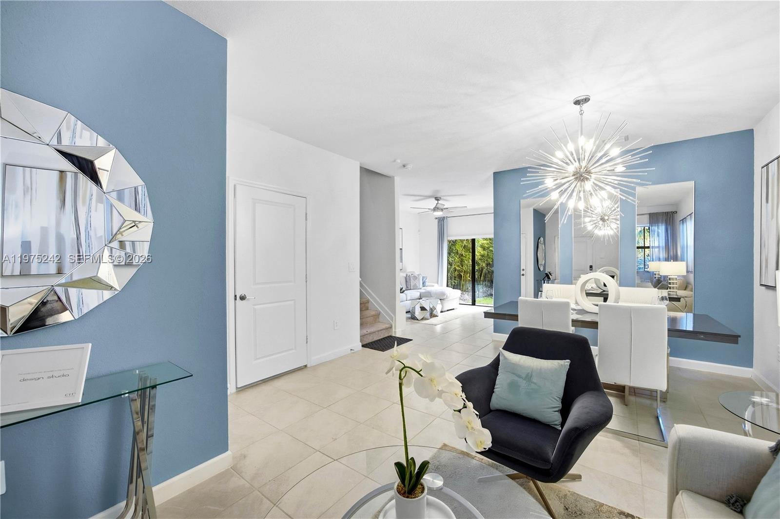 A dining area and living room feature blue accent walls, tile flooring, and modern lighting — 13054 SW 233rd Ter, Homestead FL 33032, HOMESTEAD, FL