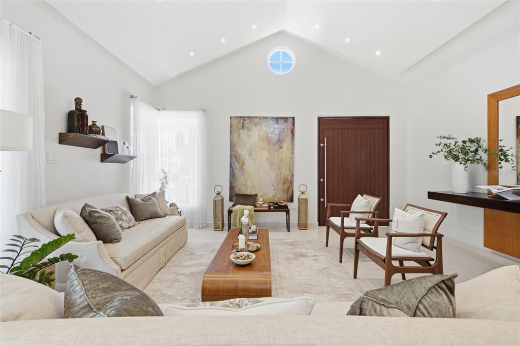 A bright living room features a vaulted ceiling, a wooden coffee table, and two armchairs — 147 CAMINO DE LOS JUNCOS, DORADO, PR