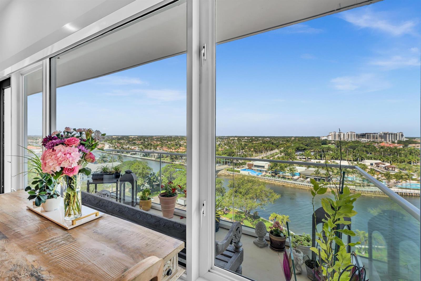 A dining area with a wooden table overlooks a balcony, a river, and distant buildings — 701 E Camino Real # 12g, Boca Raton FL 33432, BOCA RATON, FL