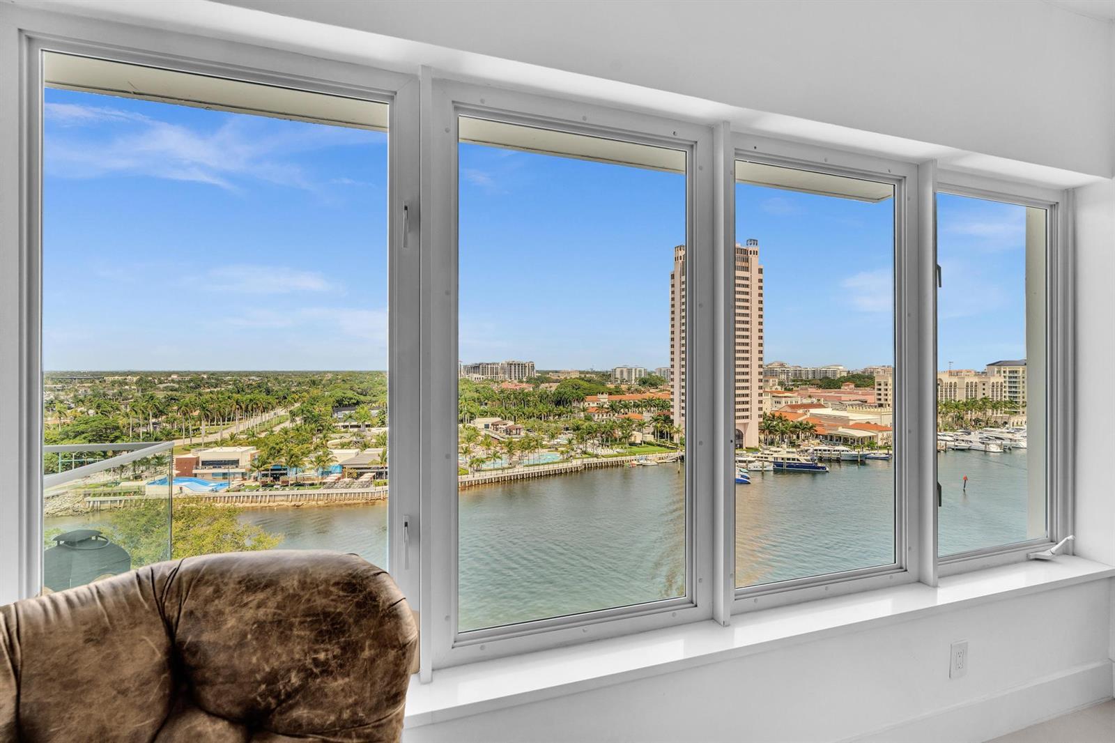 A view of a waterfront marina and city skyline seen through large living room windows — 701 E Camino Real # 12g, Boca Raton FL 33432, BOCA RATON, FL