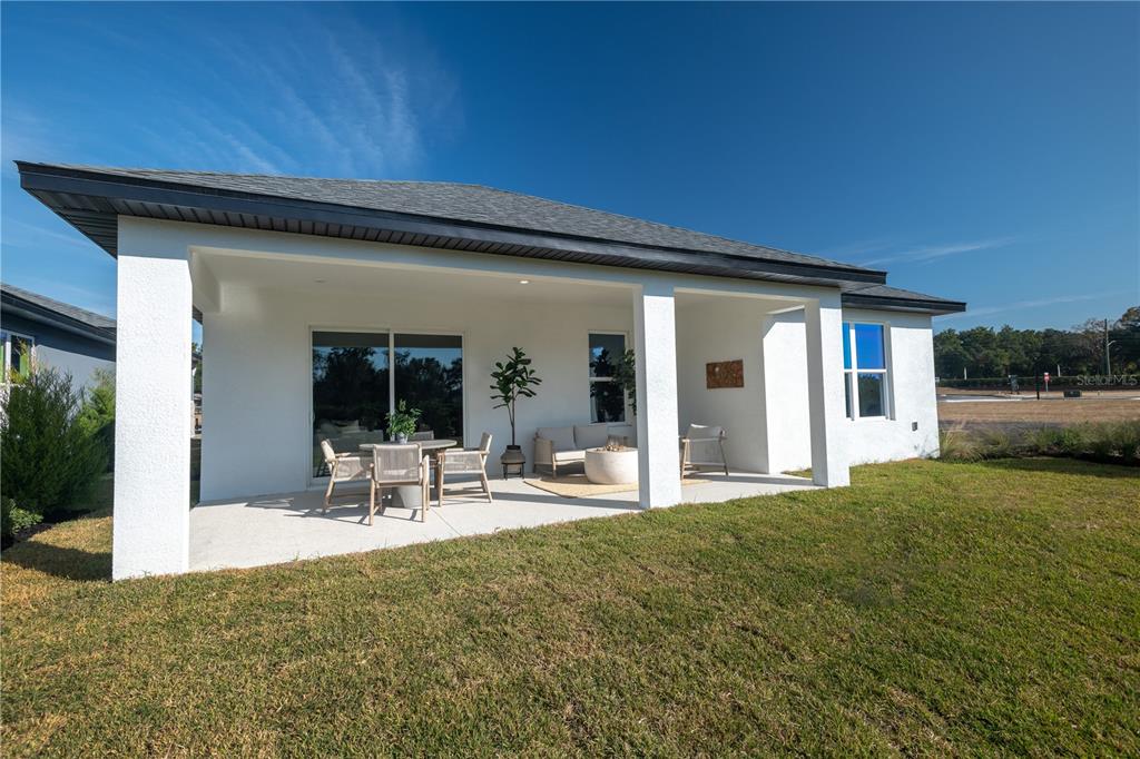 A covered concrete patio with outdoor furniture is attached to the rear of a house — 3563 NW 45TH AVENUE, OCALA, FL