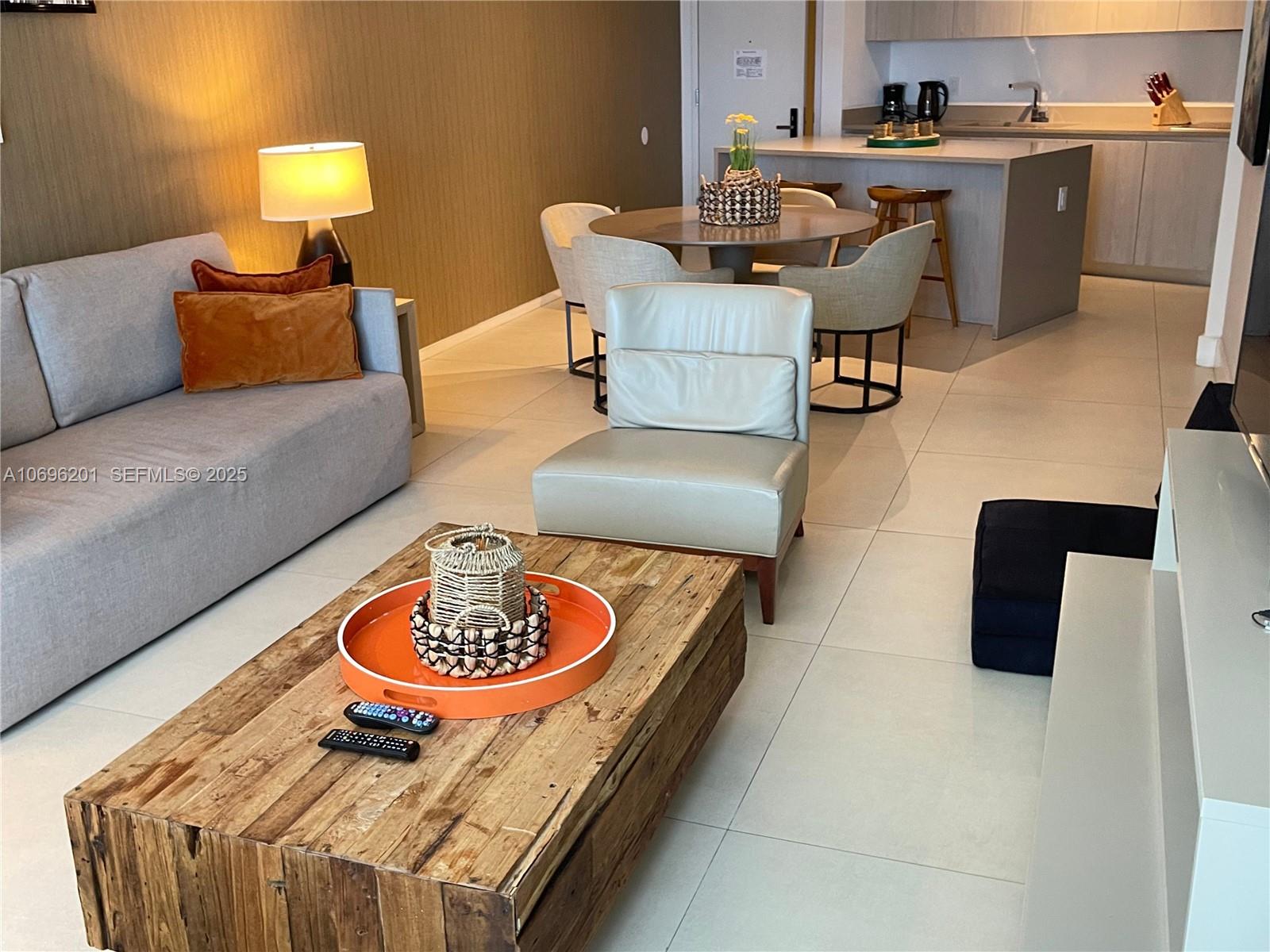 A living room features a wooden coffee table, a gray sofa, and an adjacent dining area — 4111 S OCEAN DR # 1107, Hollywood FL 33019, HOLLYWOOD, FL