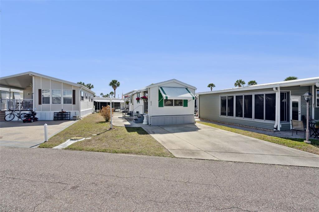 A street-level view of three manufactured homes with driveways and carports under a blue sky — 9000 US HIGHYWAY 192 UNIT 652, CLERMONT, FL