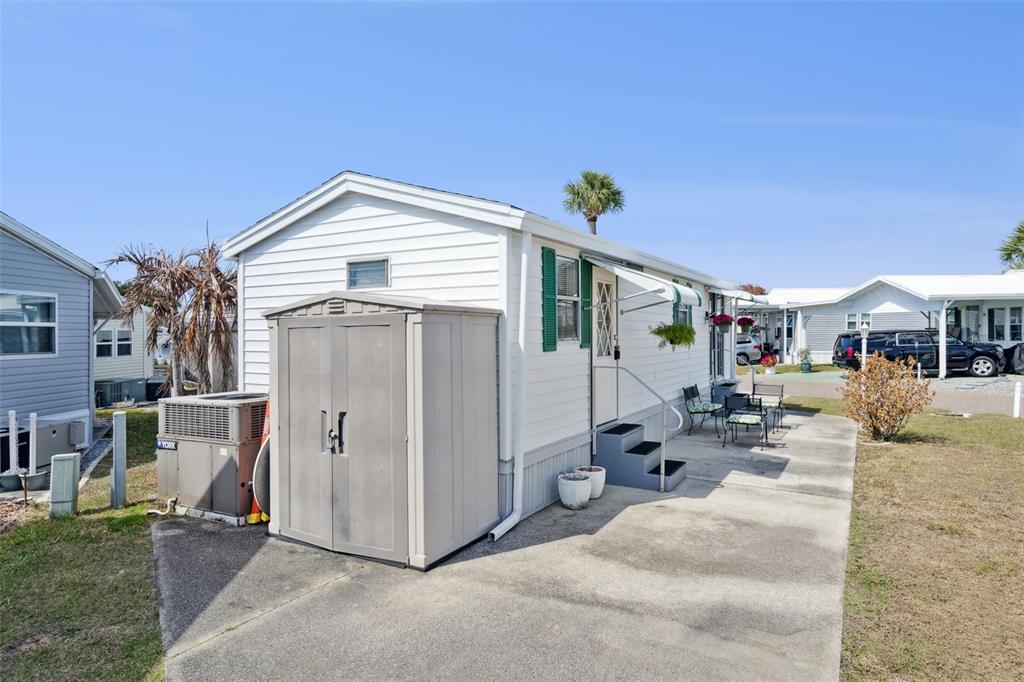 A white mobile home with a storage shed and concrete patio sits in a park — 9000 US HIGHYWAY 192 UNIT 652, CLERMONT, FL