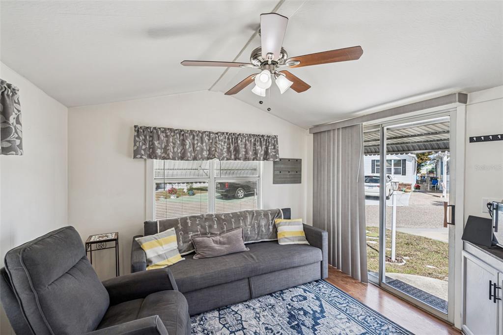 A living room features a gray sofa, a recliner, a ceiling fan, and sliding glass doors — 9000 US HIGHYWAY 192 UNIT 652, CLERMONT, FL