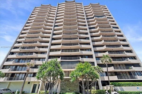 A low-angle exterior view of a tall, multi-story residential apartment building with many balconies — 4200 N Ocean Dr # 1103, Riviera Beach FL 33404, RIVIERA BEACH, FL