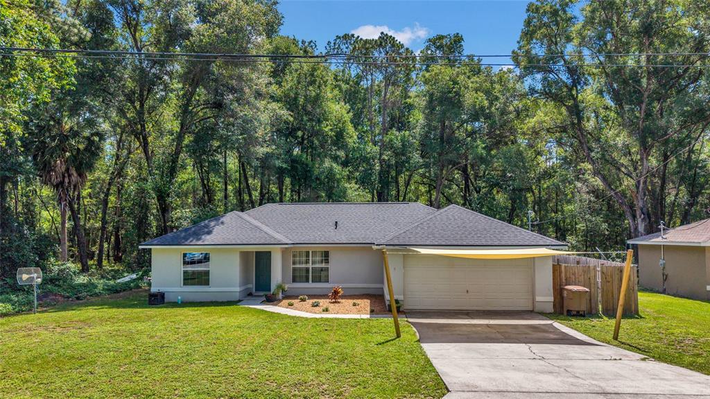 A single-story house with a gray roof, light-colored siding, and a two-car garage — 9 SEQUOIA LOOP LANE, OCKLAWAHA, FL