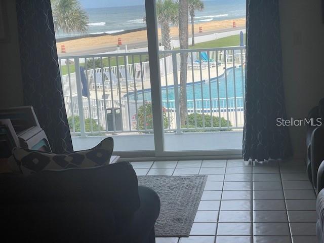 A view from a tiled room through a sliding glass door toward a pool and ocean — 3510 S OCEAN SHORE BOULEVARD UNIT 215, FLAGLER BEACH, FL