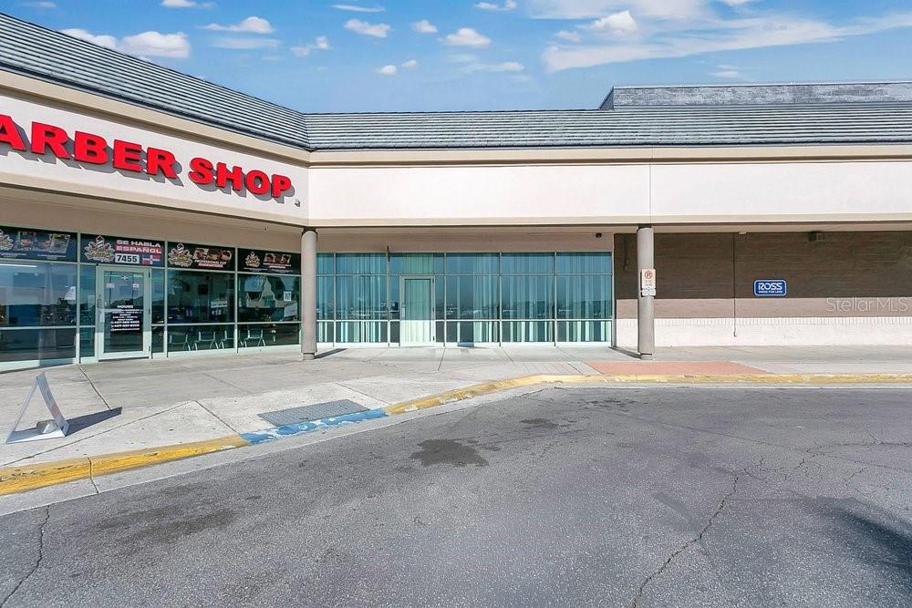 An exterior view of a strip mall featuring a barber shop and a vacant storefront — 7429 WEST COLONIAL DRIVE, ORLANDO, FL