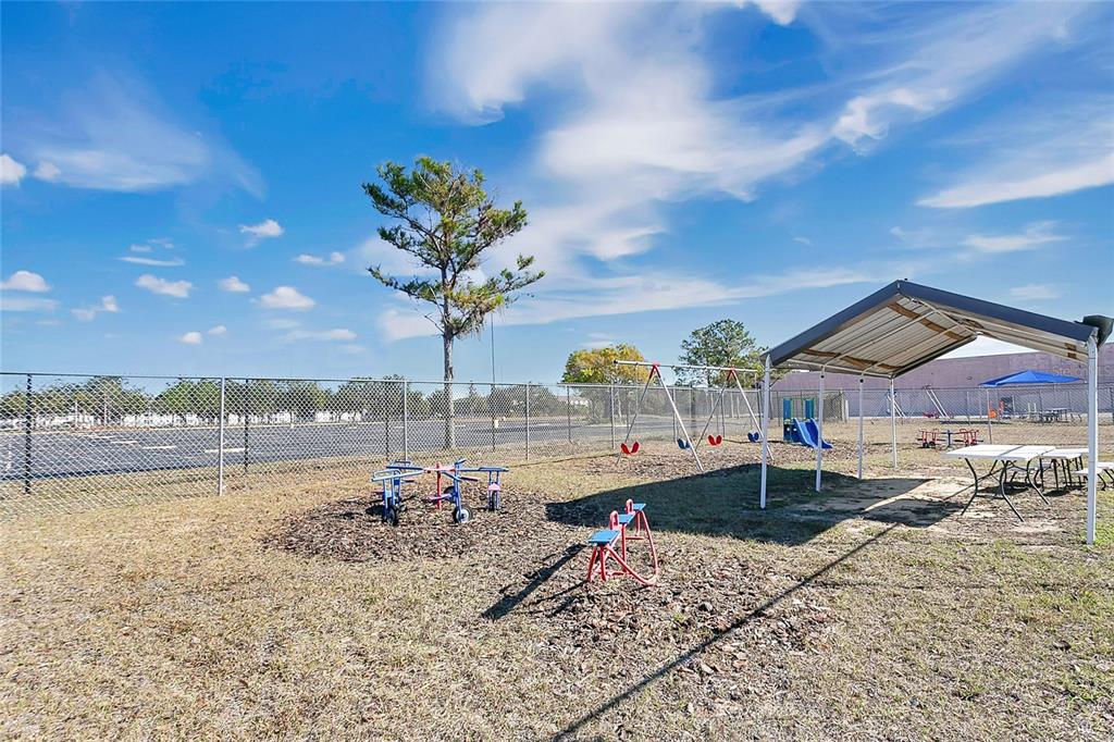 A fenced outdoor playground features a covered picnic area, swing set, and various play equipment — 7429 WEST COLONIAL DRIVE, ORLANDO, FL