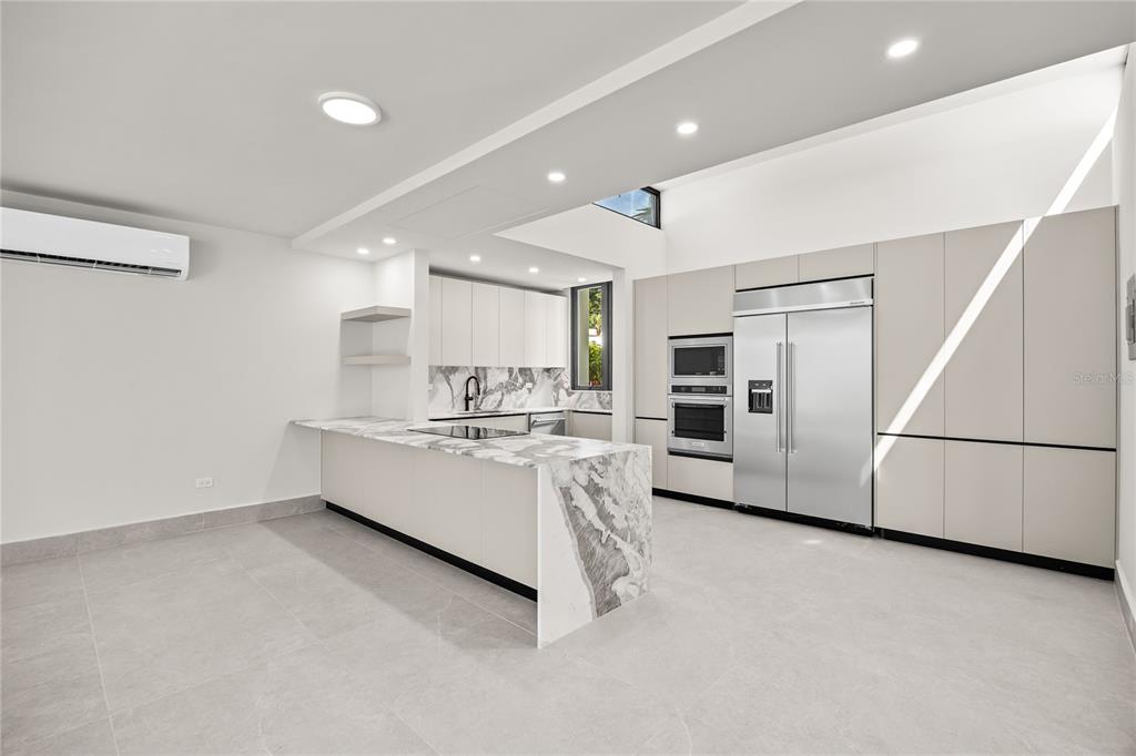 A modern kitchen features a marble waterfall island, stainless steel appliances, and light-colored cabinetry — La Villa de Torrimar REY JORGE 373, GUAYNABO, PR
