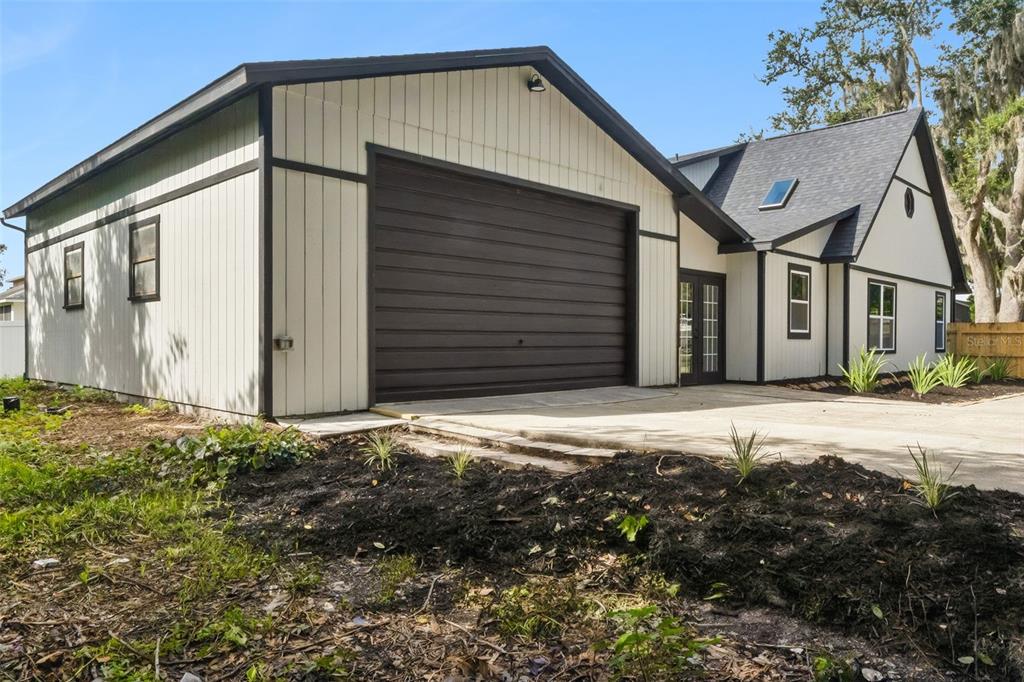 A white house with dark trim features a large garage and a concrete driveway — 2713 VICTORY PALM DRIVE, EDGEWATER, FL