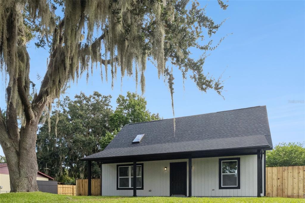 A single-story house with white vertical siding, a black roof, and a large mossy tree — 2713 VICTORY PALM DRIVE, EDGEWATER, FL