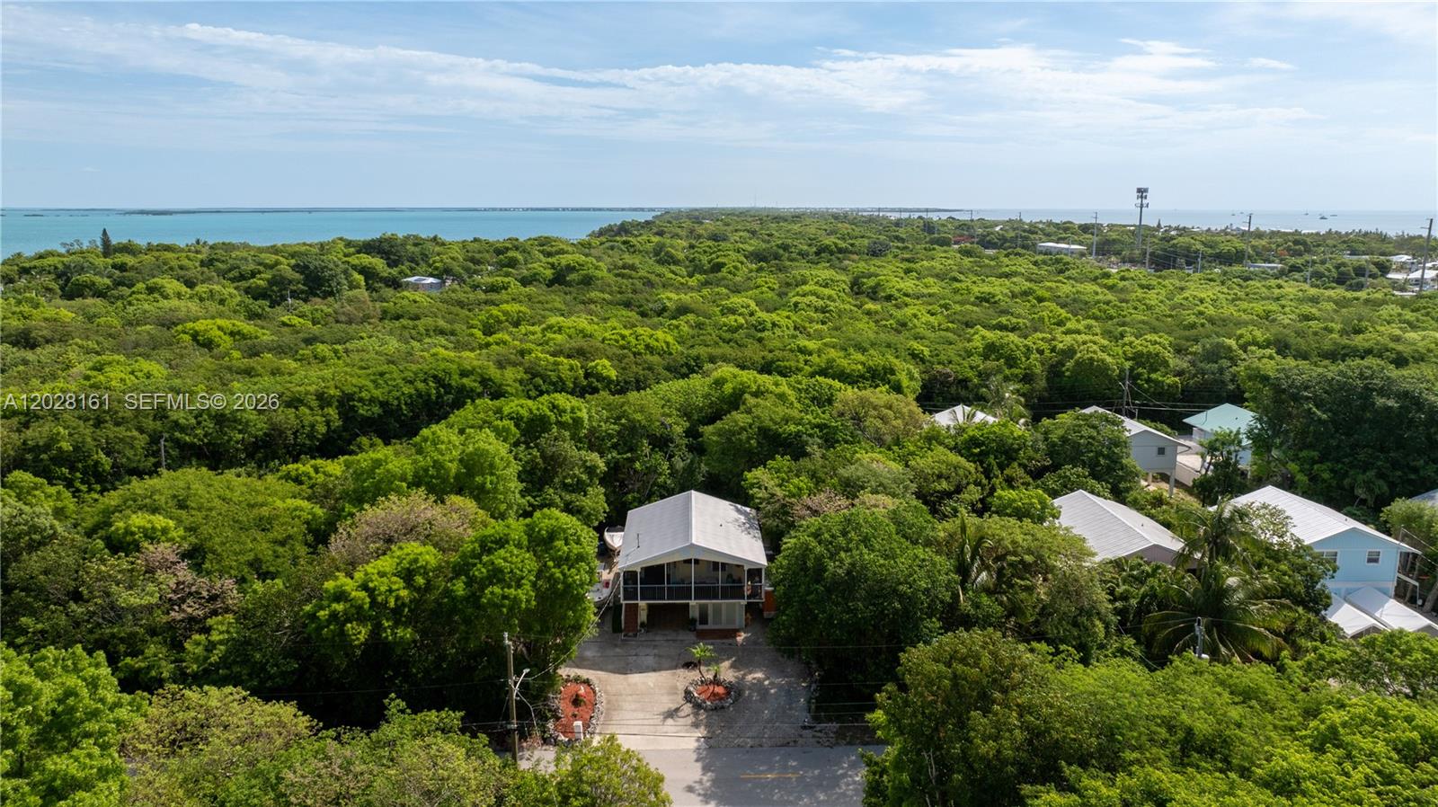An aerial view shows a house surrounded by dense trees near the ocean — 411 Mahogany Ave, Key Largo FL 33037, KEY LARGO, FL