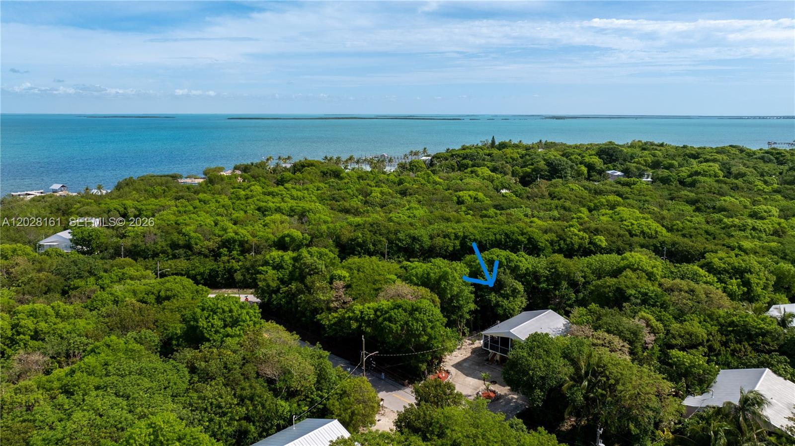 An aerial view shows a house surrounded by dense trees near a large body of water — 411 Mahogany Ave, Key Largo FL 33037, KEY LARGO, FL