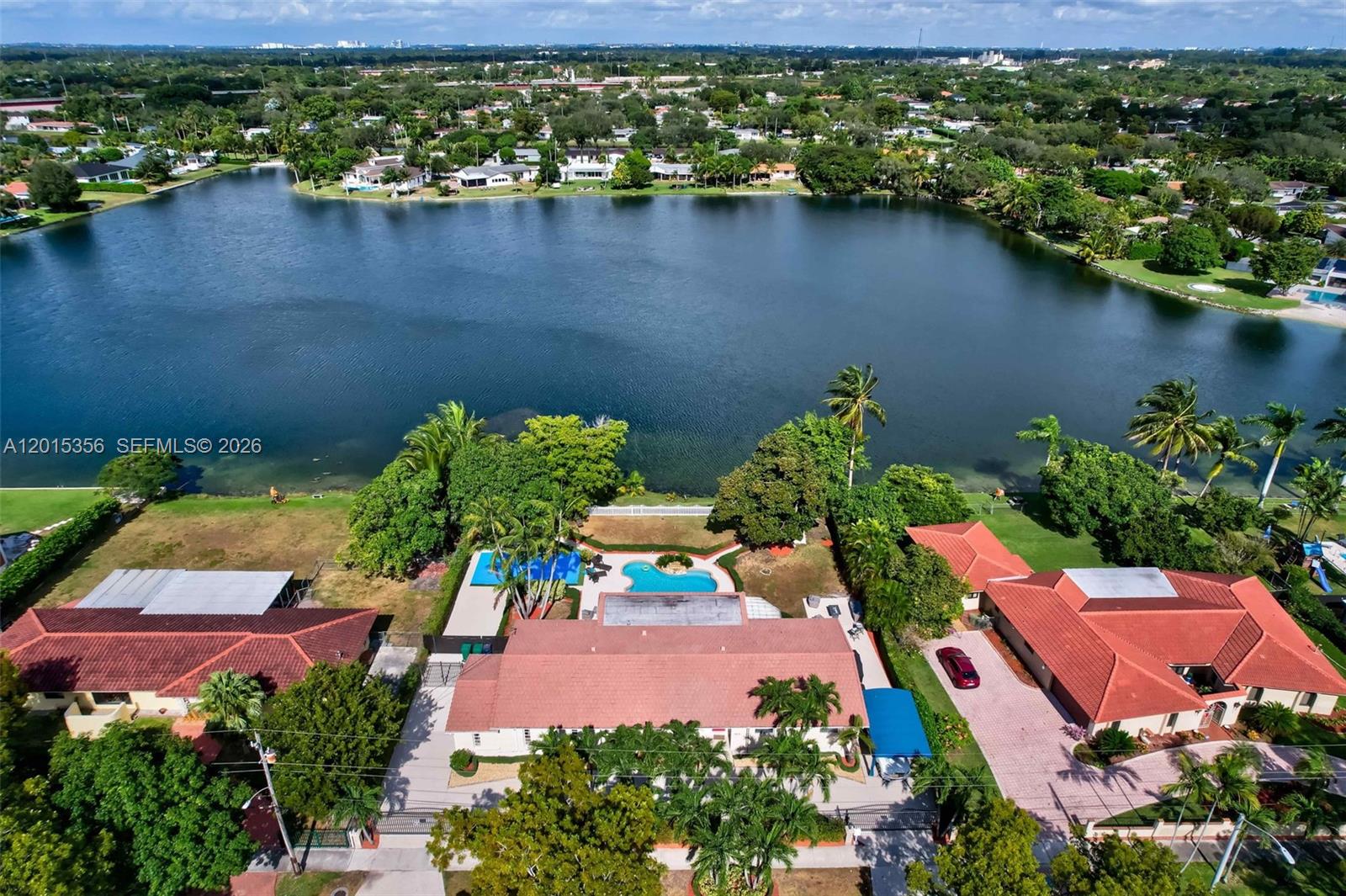 An aerial view shows a house with a red tile roof, pool, and lakefront backyard — 9261 SW 88 st, Miami FL 33176, MIAMI, FL