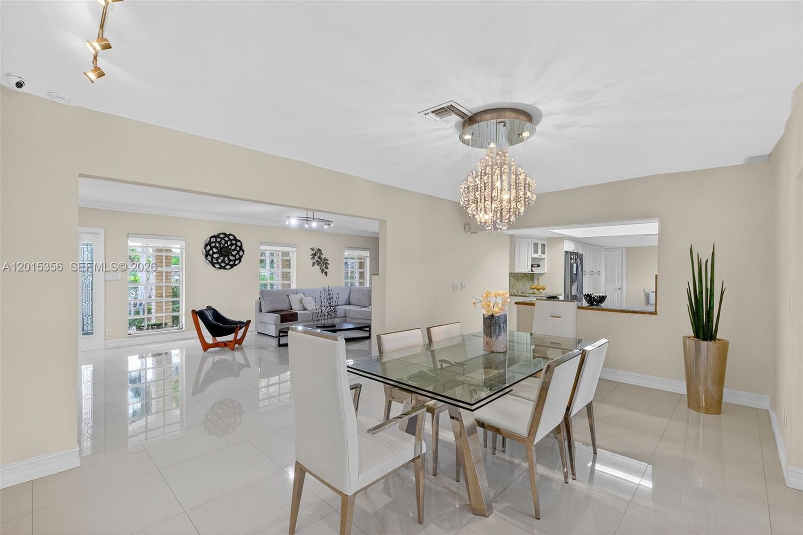 A dining area with a glass table and chandelier opens into a living room — 9261 SW 88 st, Miami FL 33176, MIAMI, FL