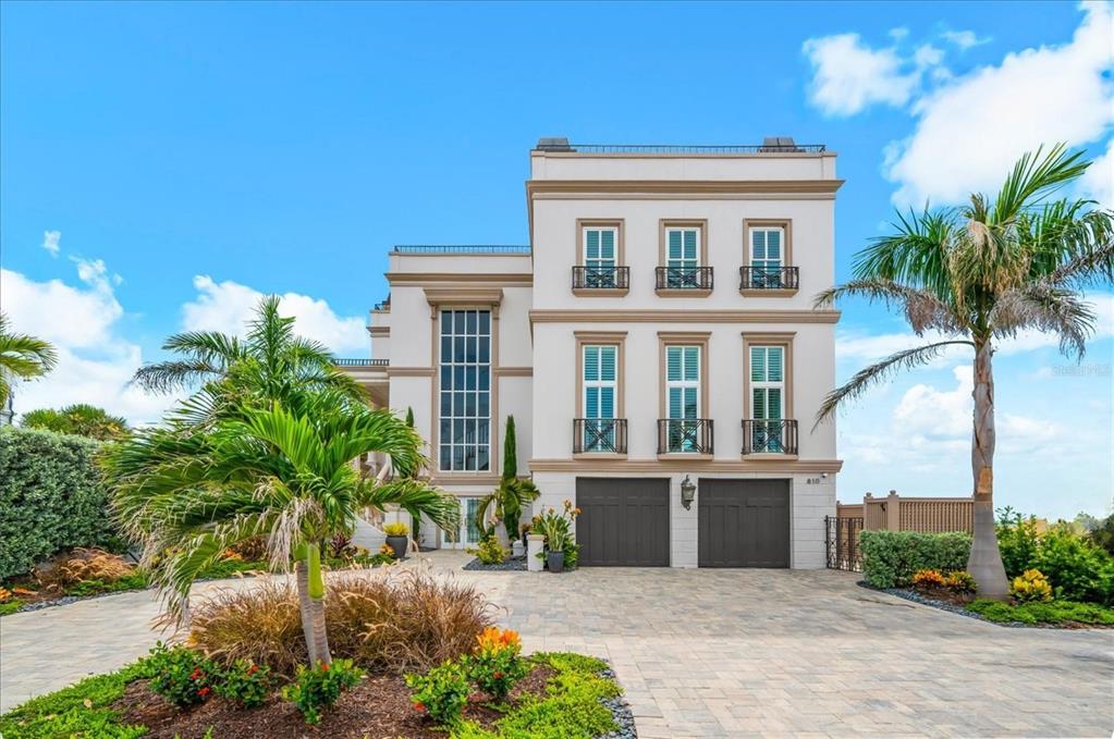A three-story house with a paved driveway, two garage doors, and a palm tree — 810 ELDORADO AVENUE, CLEARWATER BEACH, FL