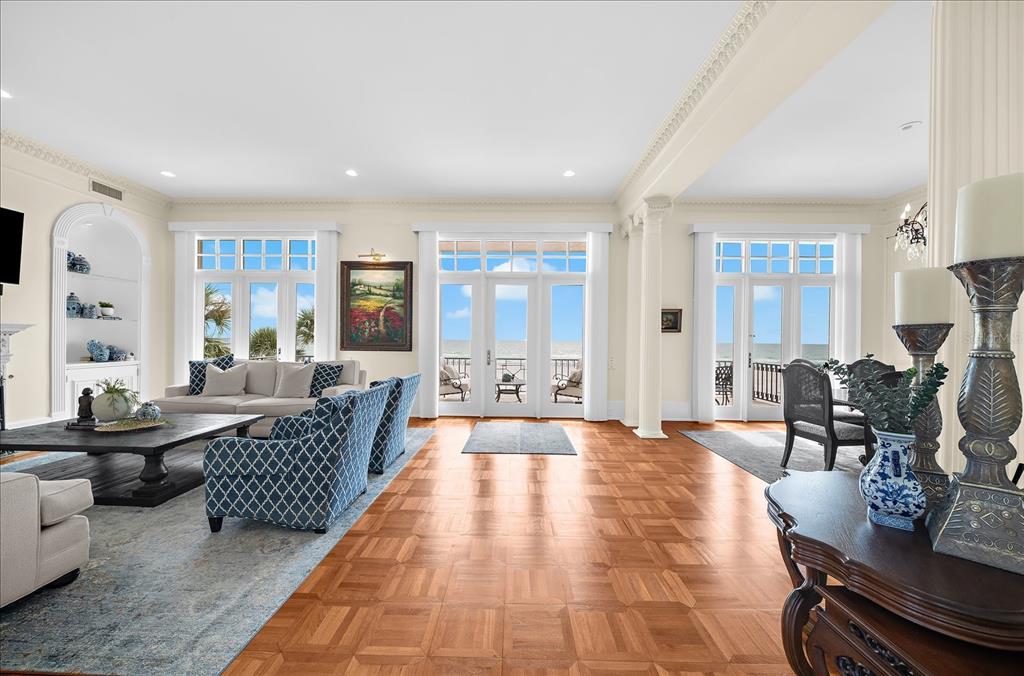 A spacious living room features parquet wood floors, white columns, and large windows overlooking the ocean — 810 ELDORADO AVENUE, CLEARWATER BEACH, FL