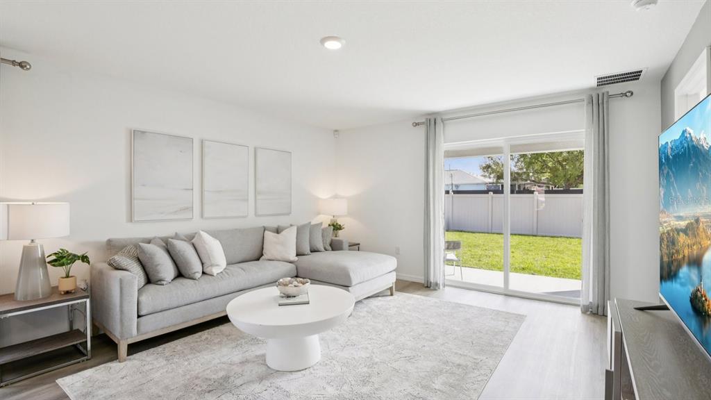A living room features a grey sectional sofa, a round coffee table, and sliding glass doors — 2387 BENDER DRIVE, ZEPHYRHILLS, FL