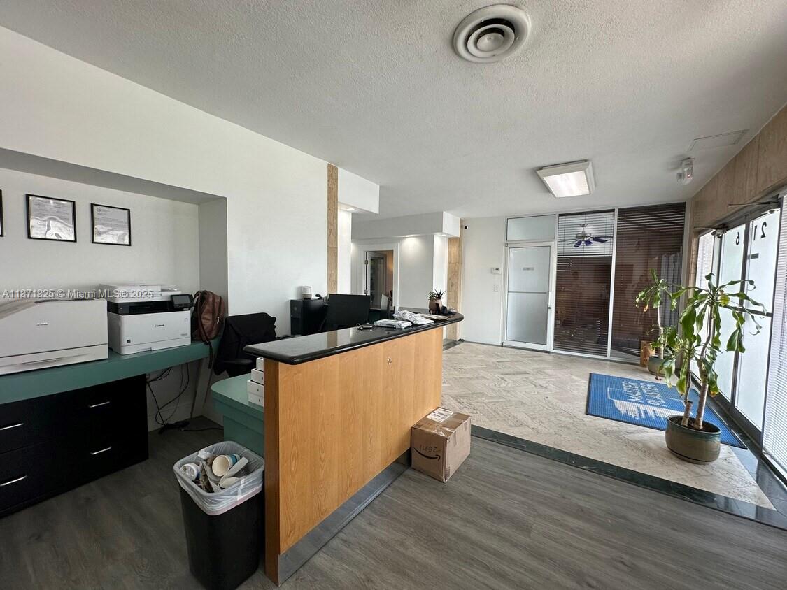 A reception area features a wooden desk, tile and wood-look flooring, and glass entry doors — 2116 N Dixie Hwy, Hollywood FL 33020, HOLLYWOOD, FL
