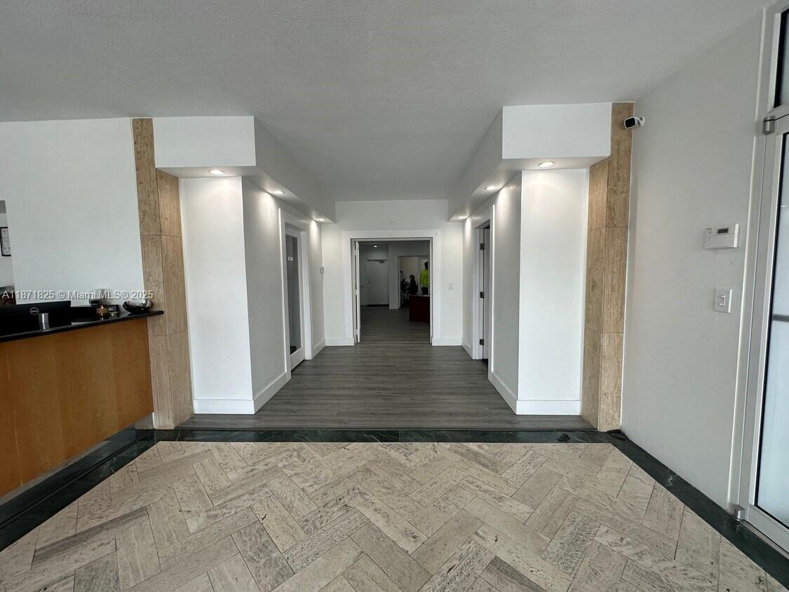 A hallway with wood-look flooring connects to a tiled foyer featuring two white support columns — 2116 N Dixie Hwy, Hollywood FL 33020, HOLLYWOOD, FL