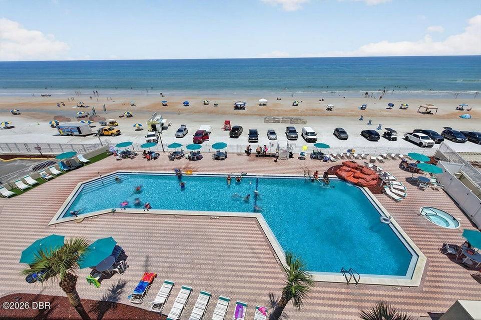 An elevated view of a swimming pool and deck overlooking a beach with parked cars — 701 S ATLANTIC AVENUE UNIT 502, DAYTONA BEACH, FL