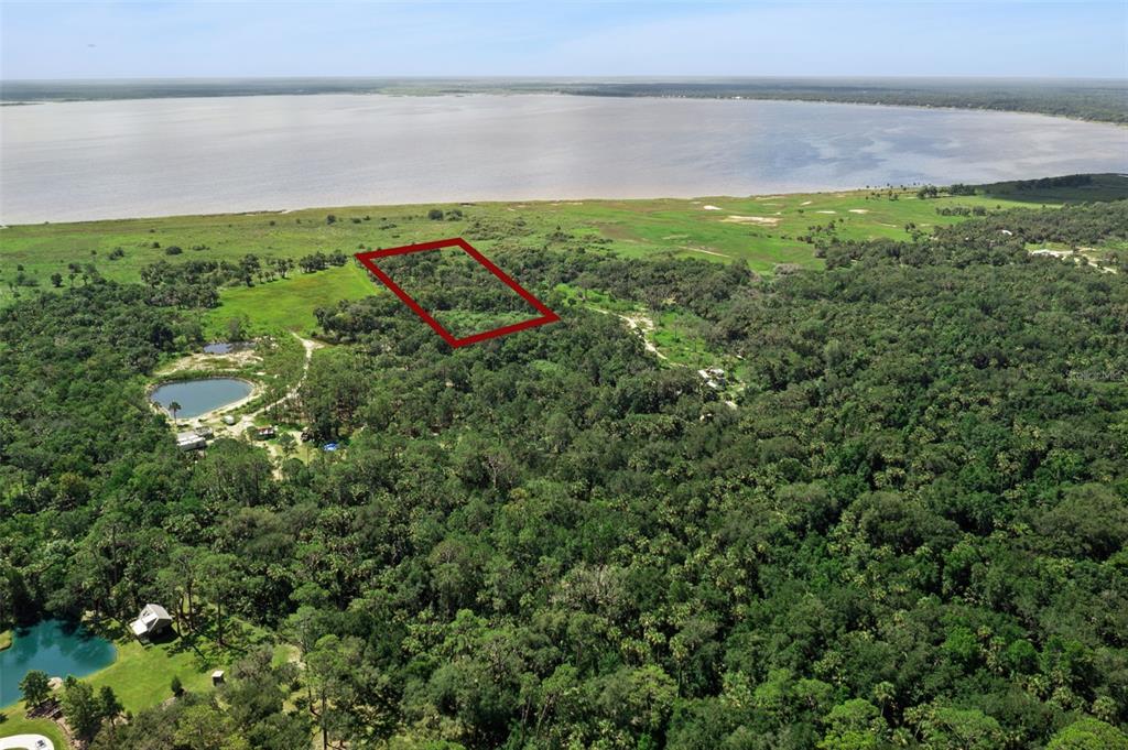 An aerial view shows a rectangular plot of land outlined in red near a lake — CANVASBACK TRAIL, GENEVA, FL