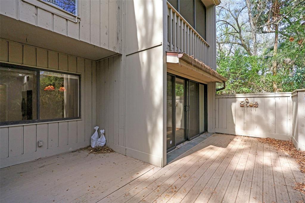 A wooden deck sits outside a two-story house with sliding glass doors and siding — 116 CROWN OAKS WAY, LONGWOOD, FL