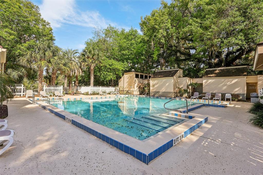 An outdoor swimming pool with a tiled edge surrounded by a concrete deck and trees — 116 CROWN OAKS WAY, LONGWOOD, FL