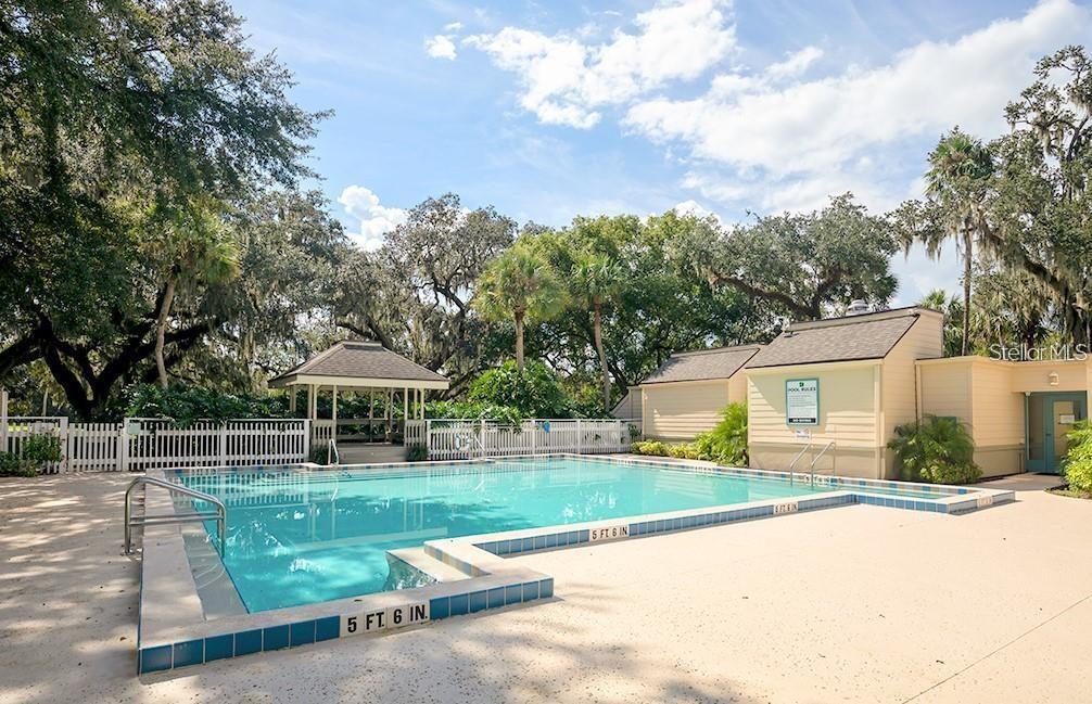 A rectangular swimming pool with a gazebo and a small building under large trees — 116 CROWN OAKS WAY, LONGWOOD, FL