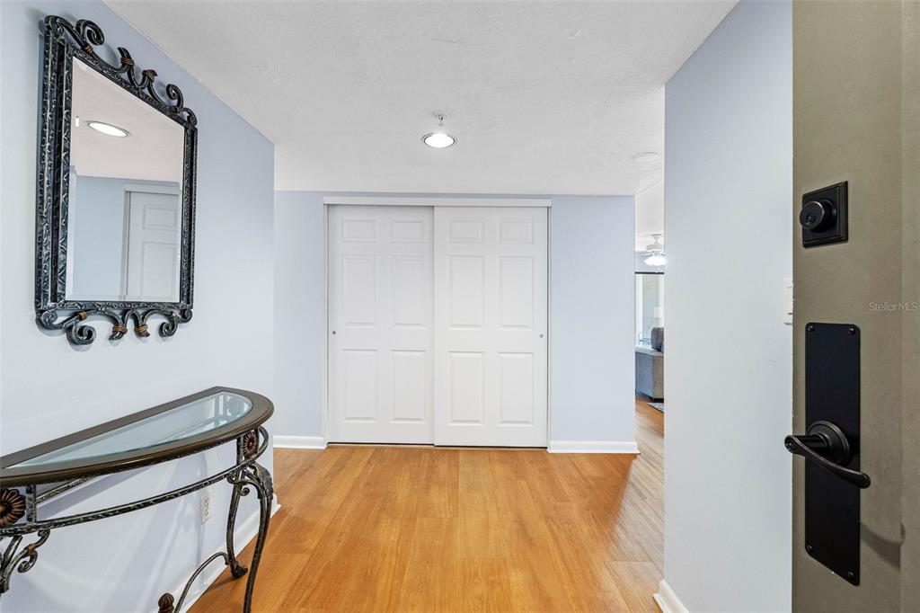 An entryway features a console table, a decorative mirror, and sliding closet doors — 1480 GULF BOULEVARD UNIT 1011, CLEARWATER BEACH, FL