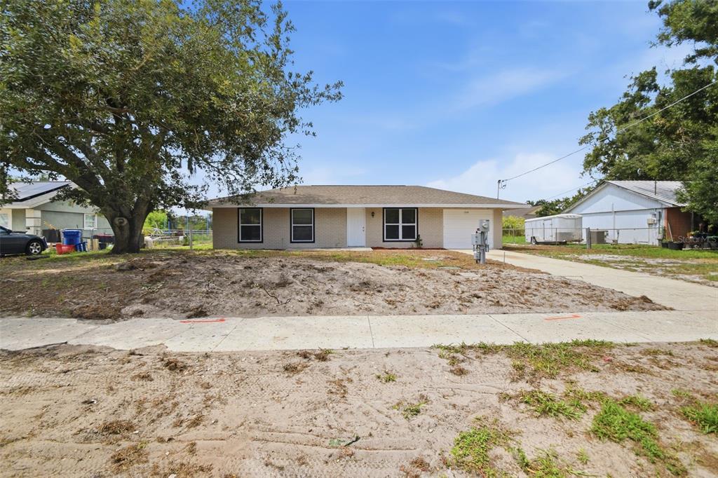 A single-story brick house with a white door, garage, and a large tree in front — 1334 ATLANTIC DRIVE, RUSKIN, FL