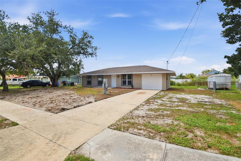 A single-story brick house with a concrete driveway and a large tree in the yard — 1334 ATLANTIC DRIVE, RUSKIN, FL