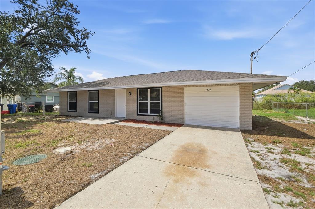 A single-story brick house with a white garage door and a concrete driveway — 1334 ATLANTIC DRIVE, RUSKIN, FL