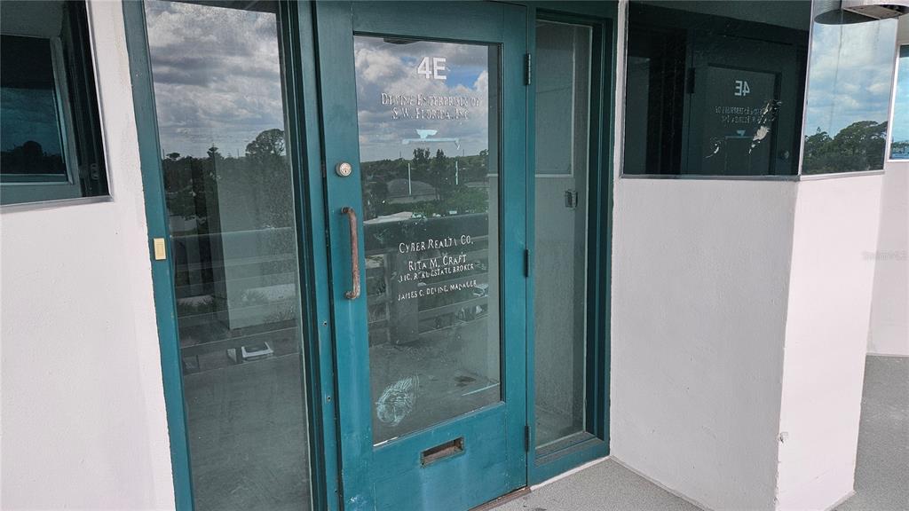 A teal-framed glass door labeled 4E leads into an office space with white walls — 1460 S MCCALL ROAD UNIT E4, ENGLEWOOD, FL