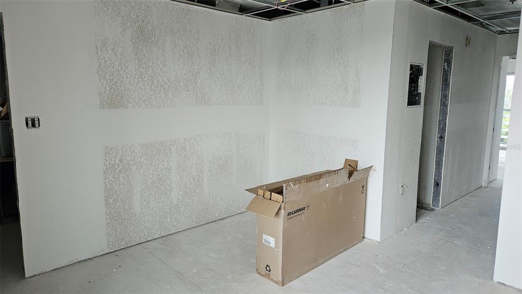 An unfinished room features white drywall with textured patches and a cardboard box on the floor — 1460 S MCCALL ROAD UNIT E4, ENGLEWOOD, FL