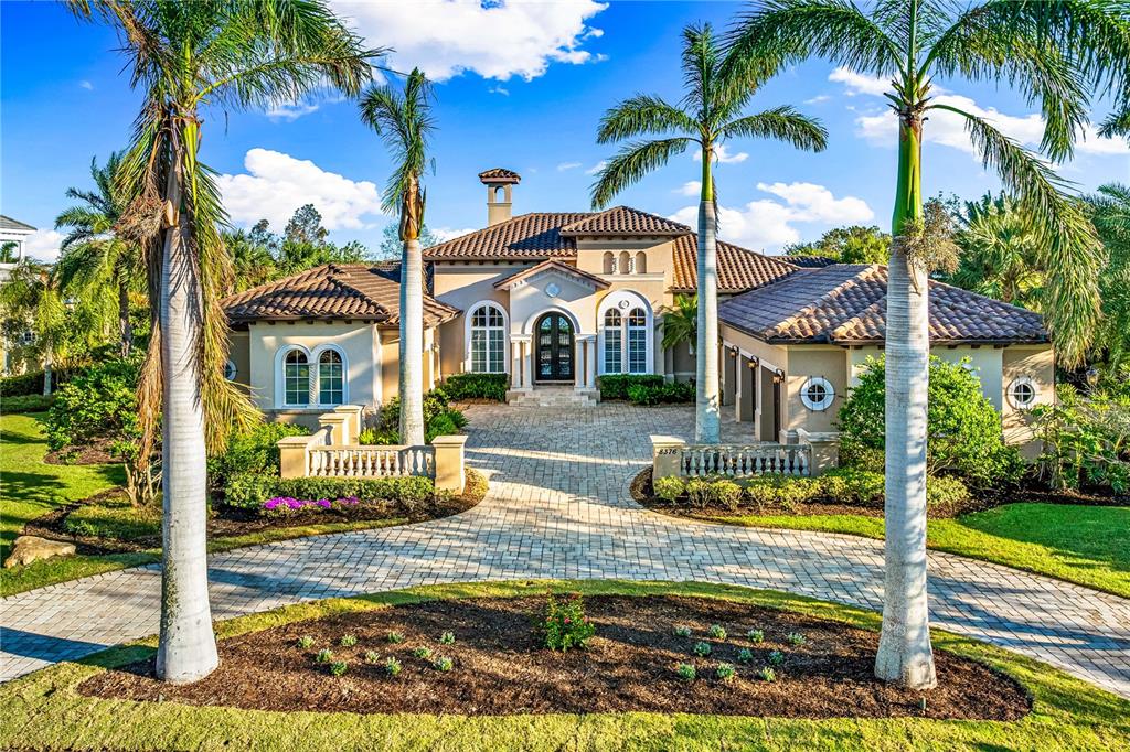 A single-story Mediterranean-style house with a paved driveway and palm trees in the front yard — 8376 CATAMARAN CIRCLE, LAKEWOOD RANCH, FL