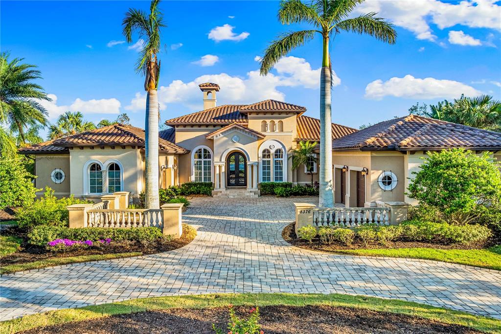 A single-story Mediterranean-style house with a tile roof, arched windows, and a paved circular driveway — 8376 CATAMARAN CIRCLE, LAKEWOOD RANCH, FL