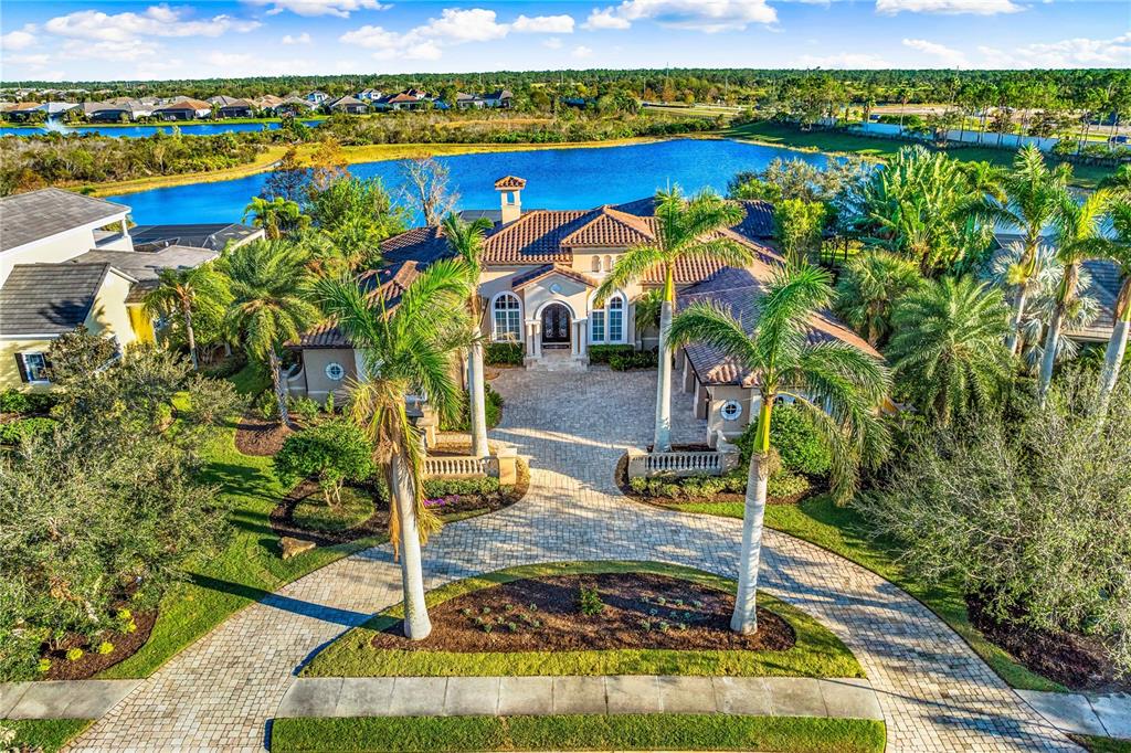 An aerial view of a Mediterranean-style house with a paved driveway and a lake behind — 8376 CATAMARAN CIRCLE, LAKEWOOD RANCH, FL