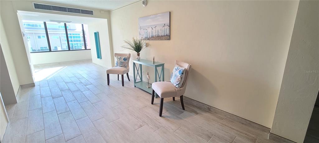 A room with light-colored tile flooring features two chairs flanking a small console table — 3051 S ATLANTIC AVENUE UNIT 1904, DAYTONA BEACH SHORES, FL